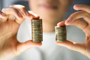 two piles of money different sizes in hands compared